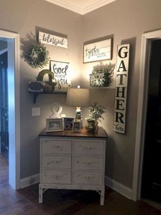 a white dresser sitting in the corner of a living room next to a lamp and pictures on the wall