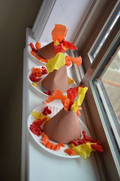 two paper plates with hats on them are sitting next to a window sill, decorated with orange and yellow flowers