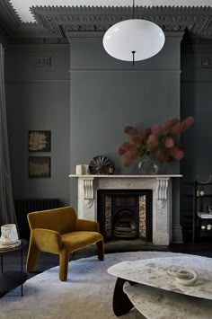 a living room with grey walls and a fire place in the center, along with a yellow chair