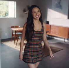 a woman in a plaid dress is walking through the room with her hand on her hip