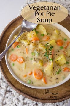 a bowl of vegetable pot pie soup with a spoon in it on a wooden plate