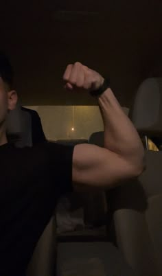 a man sitting in the back seat of a car flexing his muscles