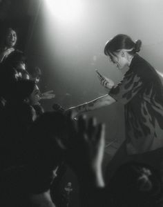 a woman standing on top of a stage with her hands in the air and people behind her