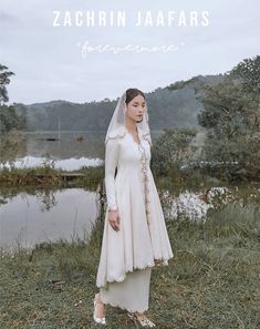 a woman wearing a white dress and veil standing in front of a lake with the words zachrin jaffars on it