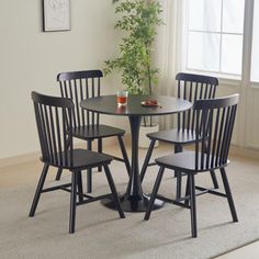 a table with four chairs and a potted plant on the floor in front of a window