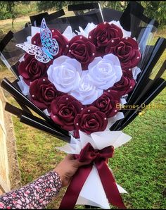 a heart shaped bouquet with red and white roses is held by a woman's hand