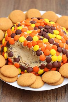 a cake covered in candy and cookies on top of a white plate with a wooden table