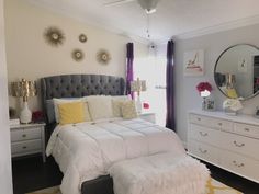 a bedroom with white bedding and yellow accents on the walls, along with gray dressers