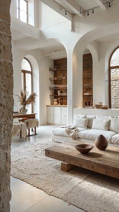 a living room filled with lots of furniture and large arched windows in the wall next to it