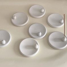 eight white bowls and spoons are arranged in a circle on a table with two chopsticks