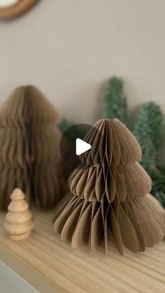 two brown paper christmas trees sitting on top of a wooden shelf