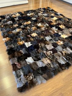 an area rug made out of several different colored furs on a wooden floor in a living room