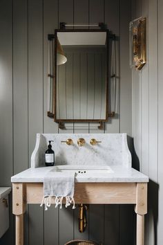 a white sink sitting under a bathroom mirror next to a wooden table with a towel on it