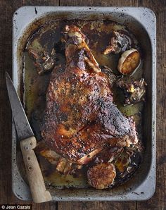 a roasting pan filled with cooked meat and vegetables on top of a wooden table