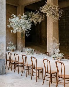 the tables are set with white flowers in vases on them and there is no one sitting at the table