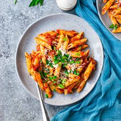 two plates of pasta with sauce and parmesan cheese