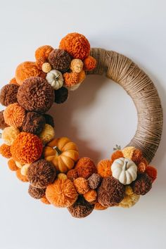 a yarn wreath decorated with pom - poms and pumpkins