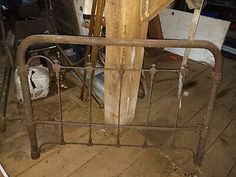 an old iron bed frame with wooden slats on the top and bottom, sitting in a room full of junk