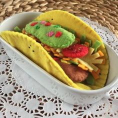 a taco stuffed with various toppings in a white bowl on a doily