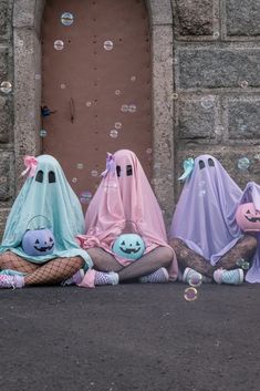 three people dressed as ghost sitting on the ground in front of a door with soap bubbles floating around them