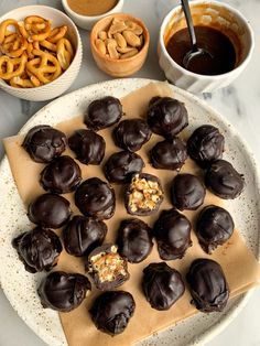 chocolate covered pretzels are on a plate next to bowls of dipping sauces