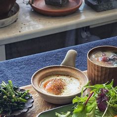 a table topped with bowls of soup and veggies next to plates of food