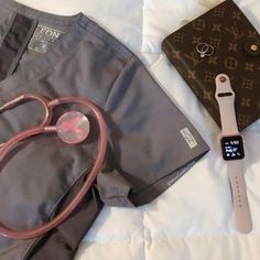 an apple watch, doctor's stethoscope and wallet on a bed