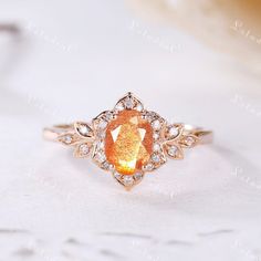 an orange diamond surrounded by white diamonds in a gold ring on top of a table