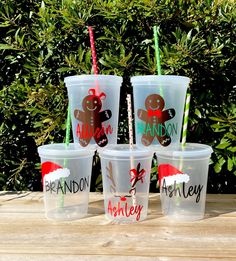 six plastic cups with straws in them on a wooden table