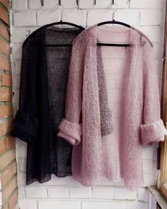 two sweaters hanging up against a brick wall