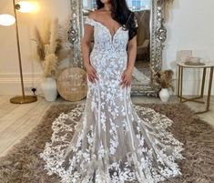 a woman standing in front of a mirror wearing a white dress with flowers on it