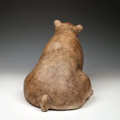 a brown bear statue sitting on top of a white table next to a gray wall