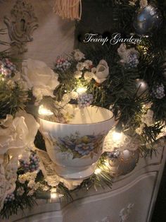 a white vase with flowers and lights in it on a table next to a christmas wreath