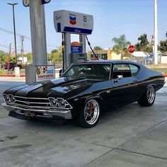 an old black car parked at a gas station