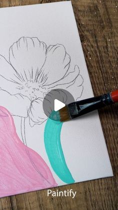 a flower is being drawn on a piece of paper with a paintbrush next to it