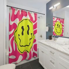 a bathroom with two shower curtains that have faces drawn on them in yellow and pink