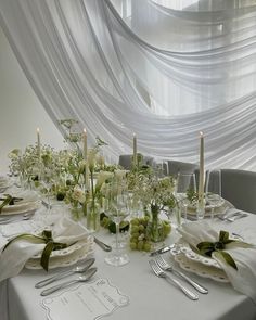 the table is set with white flowers and place settings for two people to sit at