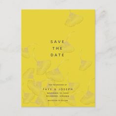 a yellow save the date card with leaves on it, in front of a marble background