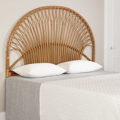 a wicker headboard with two pillows on top of it in a white bedroom