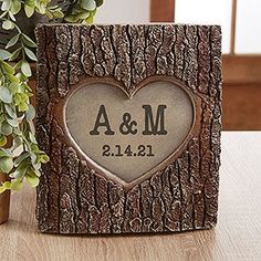 a wooden block with a heart on it next to a potted plant and vase