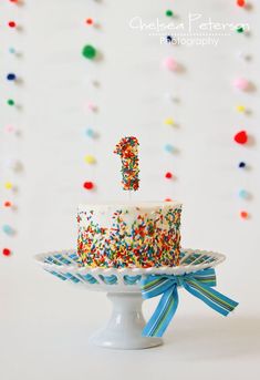 a birthday cake with sprinkles and a number one candle sticking out of it