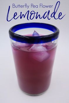 a glass filled with liquid and ice on top of a white table next to the words butterfly pea flower lemonade