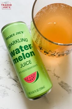 a can of watermelon juice next to a glass on a marble counter top