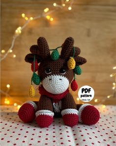 a crocheted stuffed animal sitting on top of a bed next to christmas lights