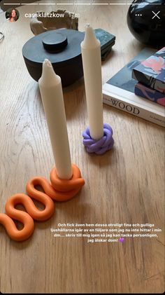 three candles sitting on top of a wooden table next to an orange and purple candle holder