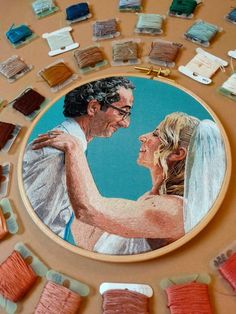 a painting of a bride and groom surrounded by thread spools on a table