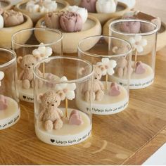 there are many small candles with teddy bears in them on the wooden table and one is filled with marshmallows