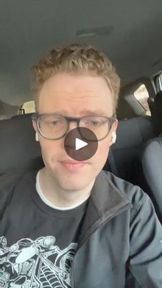 a man wearing glasses sitting in the back seat of a car