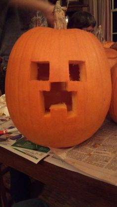 two pumpkins with faces carved into them sitting on top of a table next to each other