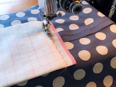 the sewing machine is working on the polka dot tablecloths that have been sewn together